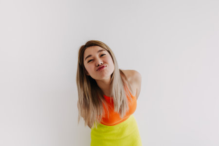 Portrait of happy cheerful asian woman in orange and lemon isolated on white.の写真素材