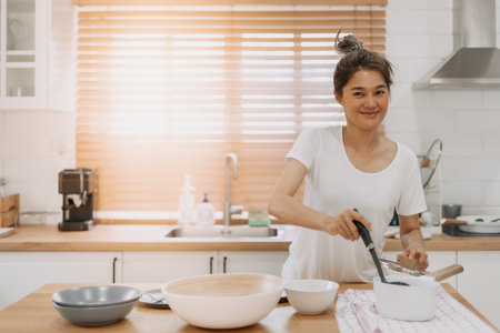 Happy asian woman serving soup into the small bowl.の写真素材