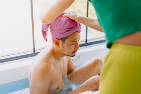 Happy childish funny asian man being take care of showering by his wife.の写真素材