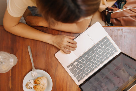 Top view of asian woman working on laptop with cake in the cafe.の写真素材
