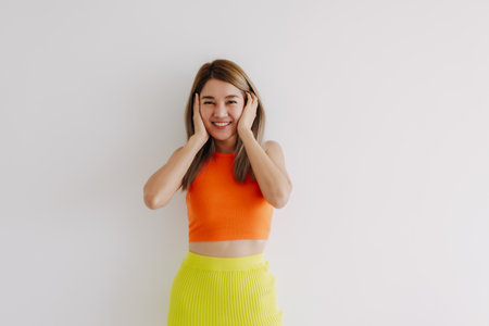Portrait of happy cheerful asian woman in orange and lemon isolated on white.の写真素材
