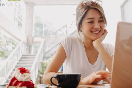 Happy freelance asian woman working with laptop in the cafe.の写真素材