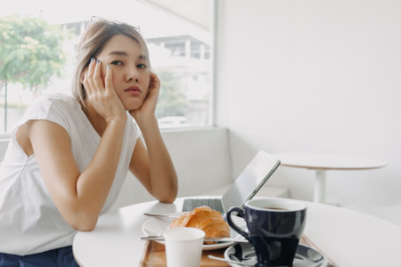 Sleepy and bored freelance asian woman working online in the cafe.の写真素材