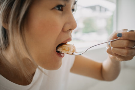 Close up funny asian face of woman eating cake in the cafe.の写真素材