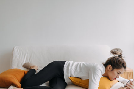Asian woman using smartphone relaxed on sofa in cold day.の写真素材