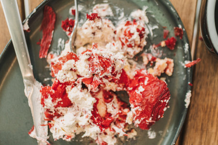 Messed up strawberry cake and cream on the dish with a cup of coffee.の写真素材