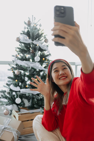Happy red shirt Asian woman making a video call for holiday greeting with her friends and family...