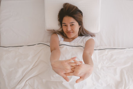 Asian woman just wake up and stretching her arms in the morning.の写真素材