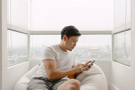 Asian man using mobile phone for killing time with social media online games and chat with friends...