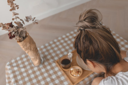 Asian woman eating bread and coffee as breakfast in apartment.の写真素材