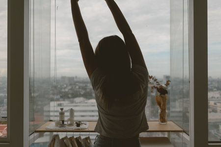 Asian woman stretching lazily by the windows in her apartment in a relax day.の写真素材
