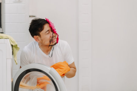 Funny crying man husband thrown with piles of clothes on his face to be washed.の写真素材