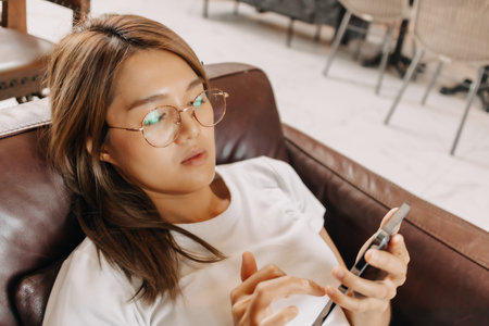Bored asian woman using smartphone boringly in the cafe.の写真素材