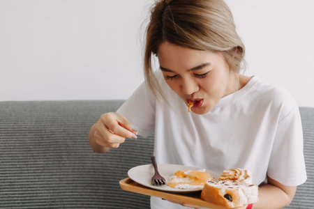 Funny face of asian woman putting breakfast into her mouth. Concept of dietary.の写真素材