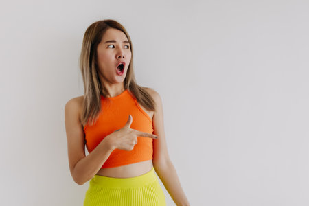 Shocked and surprised face of asian woman in orange lemon isolated on white.の写真素材