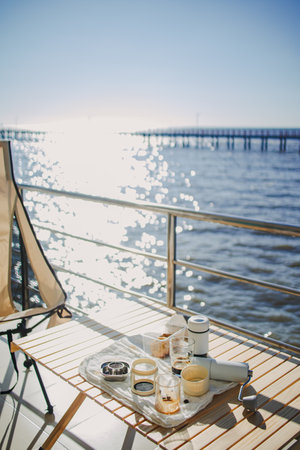Set of picnic camping with folding chair and table, Manual grinder and coffee press, beautiful bright sky and ocean vacation.の写真素材