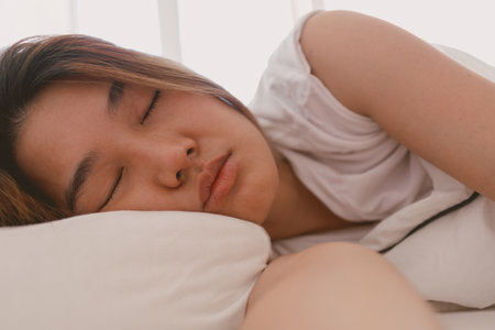Close up of lazy Asian woman just wake up but not going to get up from the bed.の写真素材