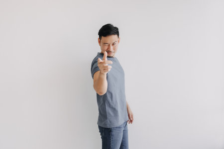 Happy asian man wears blue t-shirt and jeans winking at camera and smile.の写真素材