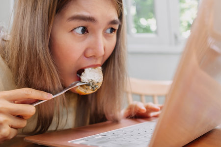 Funny face of asian woman enjoy eating snacks and cream, no worry for diet.の写真素材