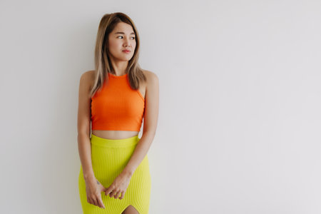 Serious upset face of asian woman in orange lemon color isolated on white.の写真素材