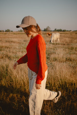 Happy asian woman in red sweater walking on the grass field to see the cows cattle and the sunset view.の写真素材