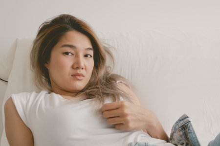 Asian woman lies and resting on the sofa, playing with her hair and relax.の写真素材
