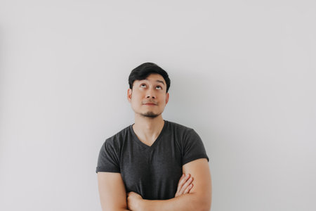 Asian man in black t-shirt crossing his arms isolated on white wall.