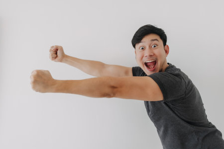 Happy and cheering funny face Asian man in black t-shirt isolated on white background.