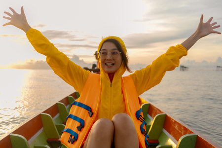 Happy Asian woman in yellow hoody enjoy ridding boat in the morning.の写真素材