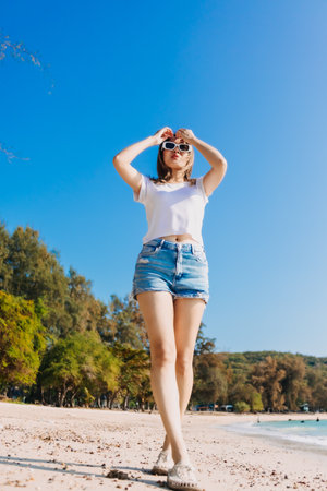 Cheerful asian woman walking along the beach and clear sky.の写真素材