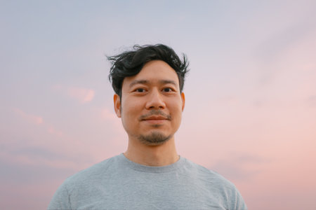 Portrait of asian man standing with smooth colorful sunset sky.の写真素材