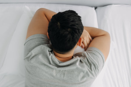 Serious and depressed asian man overthinking the problems lying on the bed.の写真素材