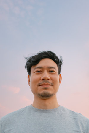 Portrait of asian man standing with smooth colorful sunset sky.の写真素材