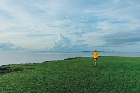 Asian woman in yellow hood walking on the wetland, Thale Noi, Thailand.の写真素材