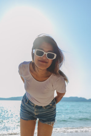 Happy asian woman enjoy taking photo on sunny beach. Thailand.の写真素材