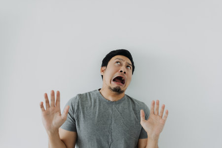 Shocked and disappoint face of asian man in grey t-shirt isolated on white.の写真素材