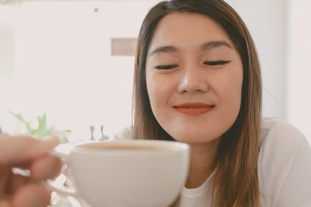 Asian woman is receiving a coffee cup and drink.の写真素材