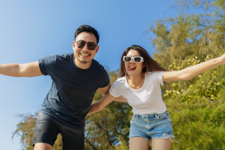 Cheerful and playful asian couple lover is taking selfie photo with bright sky.の写真素材