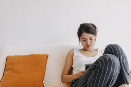 Asian woman using mobile phone and relax sit and lying on the sofa .の写真素材