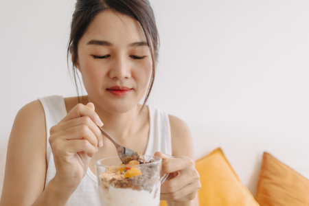 Close up happy Asian woman eating healthy dessert made of yogurt.の写真素材