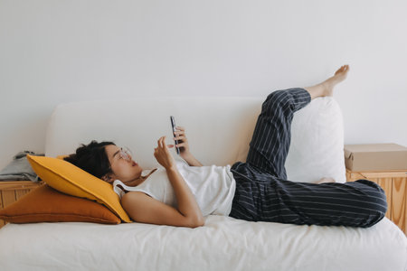 Asian woman using mobile phone and relax sit and lying on the sofa .の写真素材