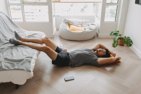 Asian man napping on the floor with leg lean on the sofa in the living room.の写真素材