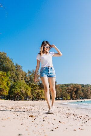 Cheerful asian woman walking along the beach and clear sky.の写真素材