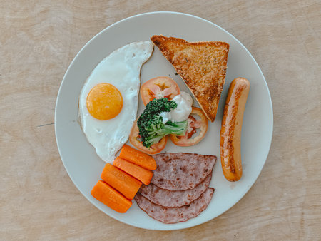American breakfast sets of fried eggs, toasts, carrots and hams on white table.の写真素材