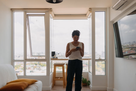 Asian woman walking around her room and chat with the mobile phone.