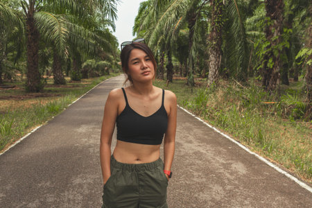 Asian Woman in cargo pants and tank-top in tropical palm farm.の写真素材