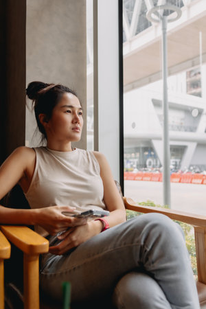 Asian woman sitting alone in the cafe, taking her time, waiting for someone.の写真素材