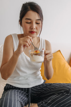 Close up happy Asian woman eating healthy dessert made of yogurt.の写真素材