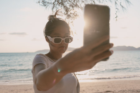 Asian woman is taking selfie photo of herself at the beach.の写真素材