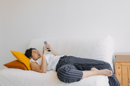 Asian woman using mobile phone and relax sit and lying on the sofa .の写真素材